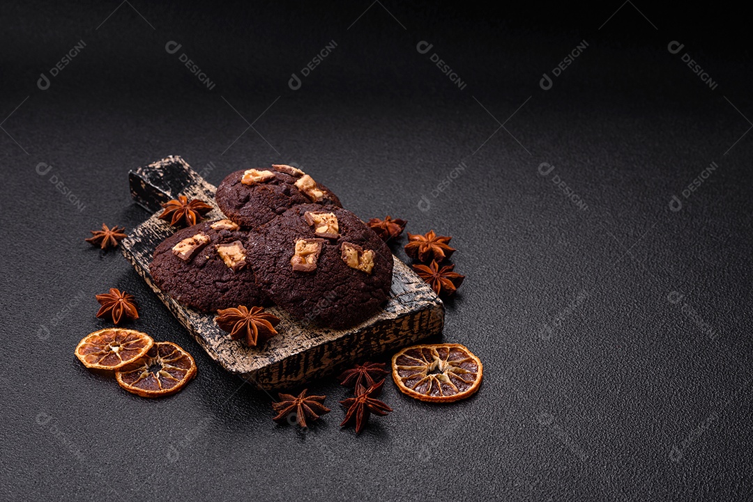 A imagem mostra biscoitos de chocolate, possivelmente cookies, decorados com pedaços de chocolate