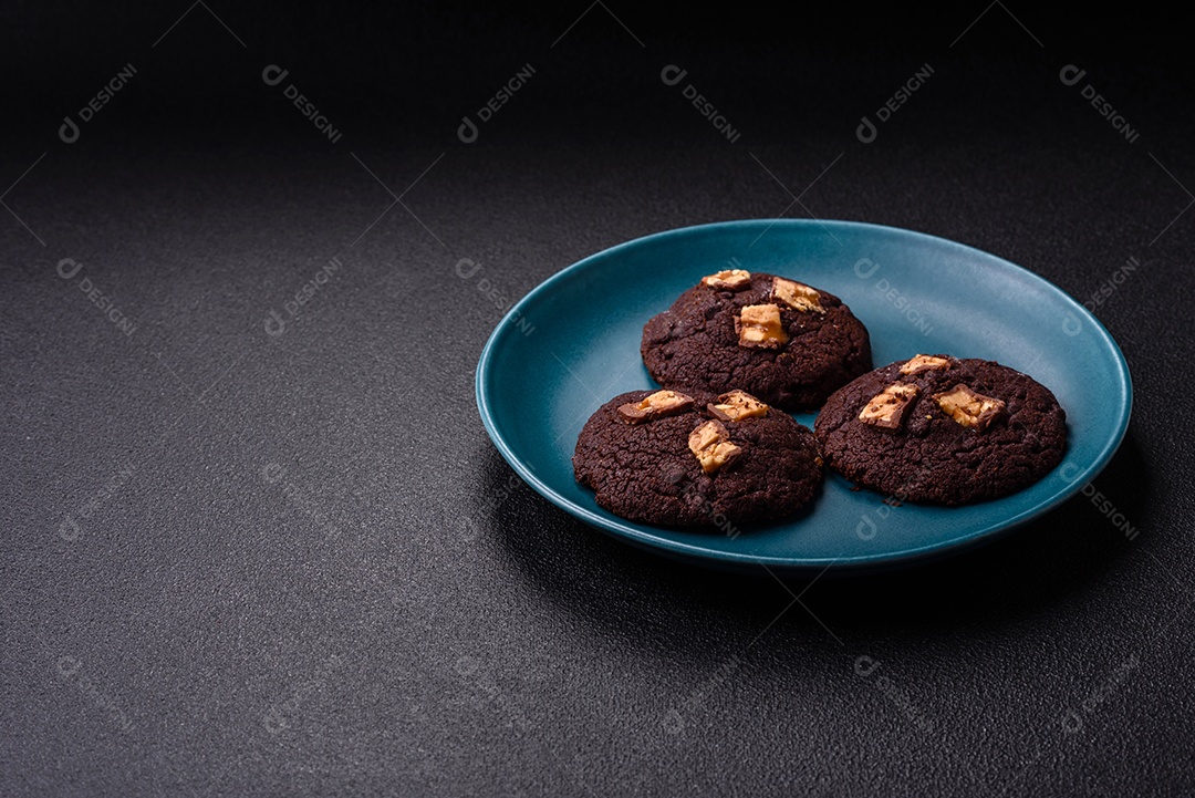 A imagem mostra biscoitos de chocolate, possivelmente cookies, decorados com pedaços de chocolate