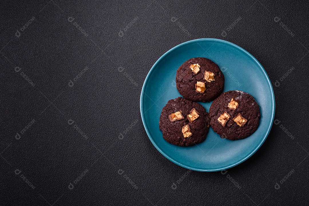 A imagem mostra biscoitos de chocolate, possivelmente cookies, decorados com pedaços de chocolate