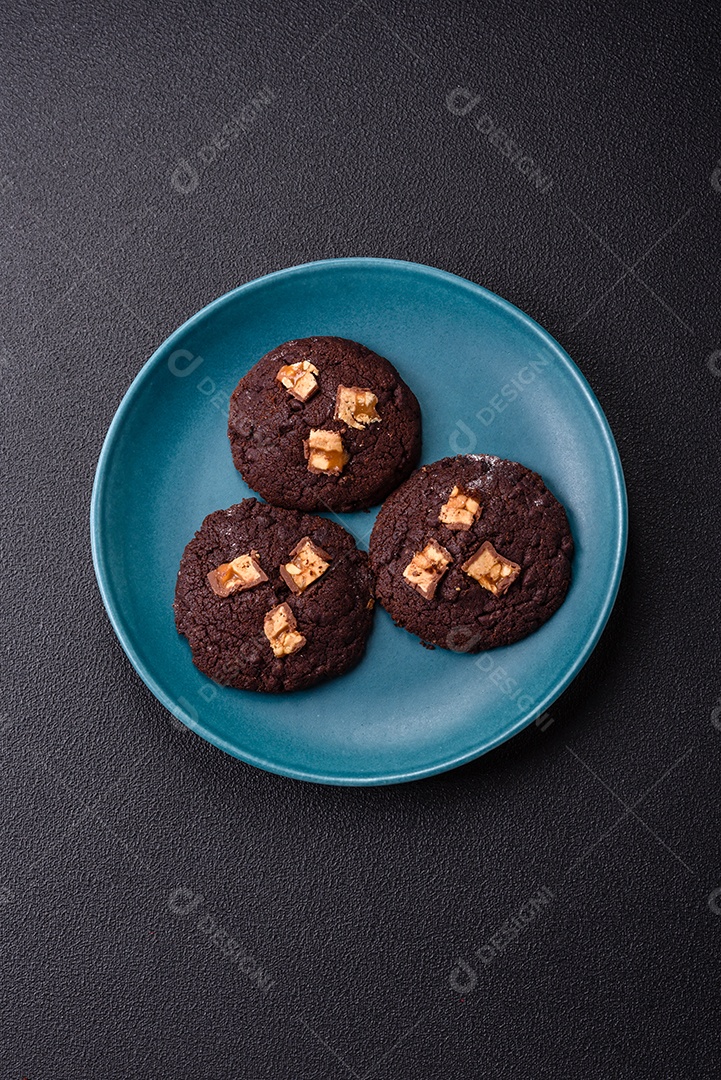 A imagem mostra biscoitos de chocolate, possivelmente cookies, decorados com pedaços de chocolate