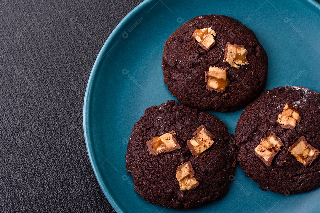 A imagem mostra biscoitos de chocolate, possivelmente cookies, decorados com pedaços de chocolate