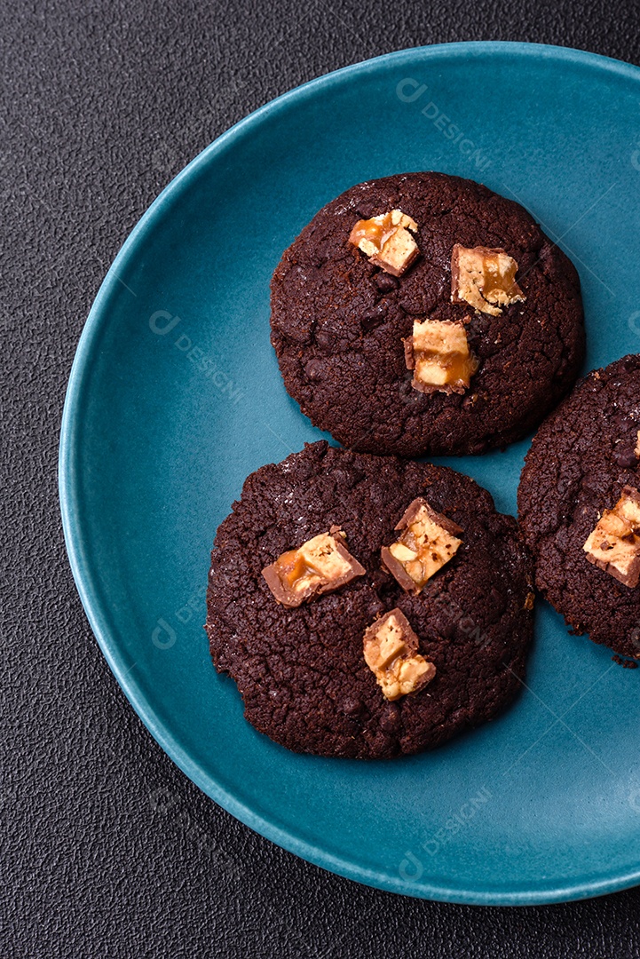 A imagem mostra biscoitos de chocolate, possivelmente cookies, decorados com pedaços de chocolate