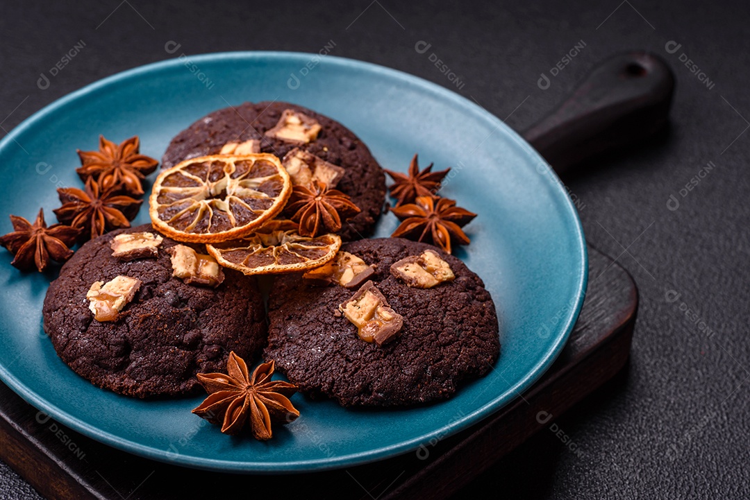 A imagem mostra biscoitos de chocolate, possivelmente cookies, decorados com pedaços de chocolate