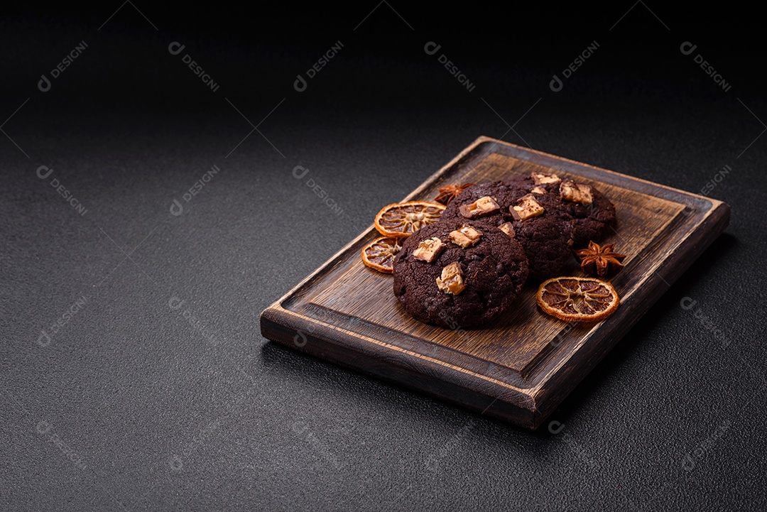 A imagem mostra biscoitos de chocolate, possivelmente cookies, decorados com pedaços de chocolate