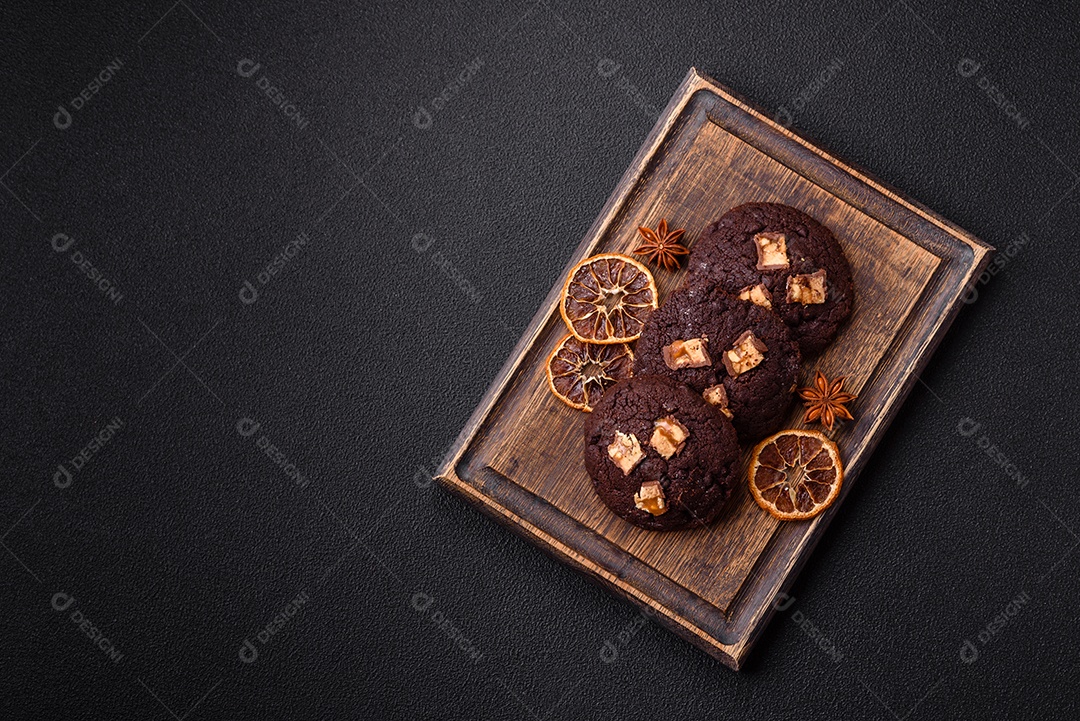 A imagem mostra biscoitos de chocolate, possivelmente cookies, decorados com pedaços de chocolate