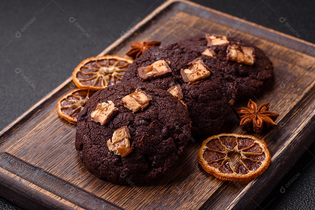 A imagem mostra biscoitos de chocolate, possivelmente cookies, decorados com pedaços de chocolate
