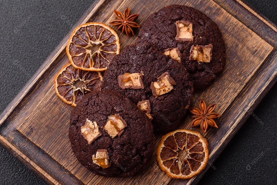 A imagem mostra biscoitos de chocolate, possivelmente cookies, decorados com pedaços de chocolate