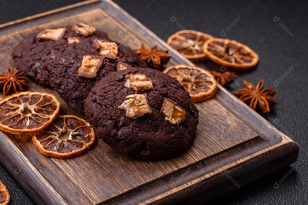 A imagem mostra biscoitos de chocolate, possivelmente cookies, decorados com pedaços de chocolate