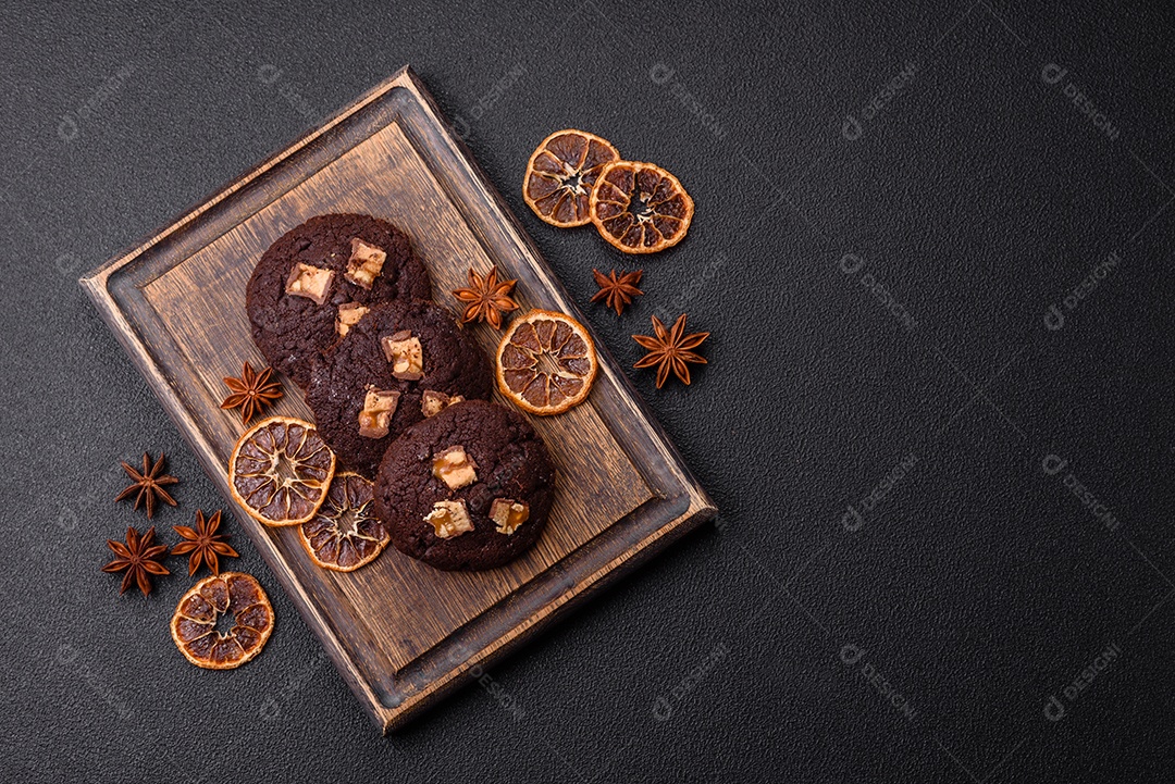 A imagem mostra biscoitos de chocolate, possivelmente cookies, decorados com pedaços de chocolate
