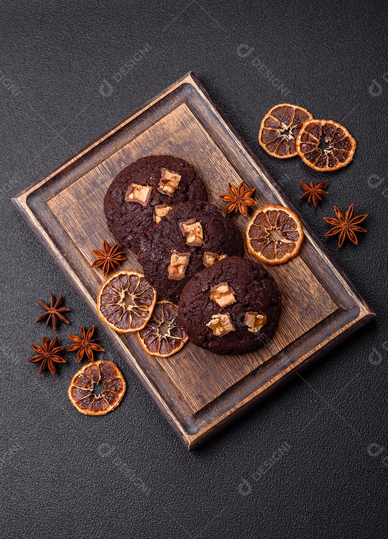 A imagem mostra biscoitos de chocolate, possivelmente cookies, decorados com pedaços de chocolate
