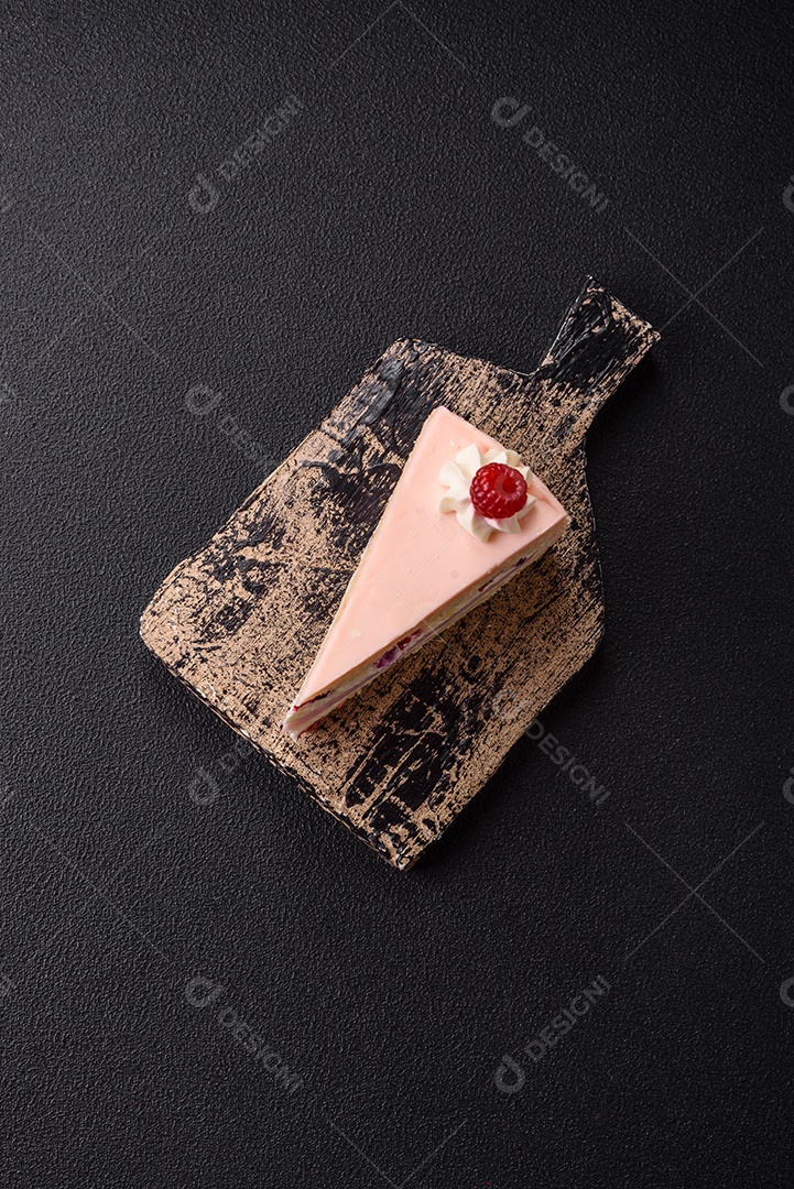 A imagem mostra uma fatia de bolo ou torta com cobertura rosa claro e um topo decorado com uma framboesa fresca