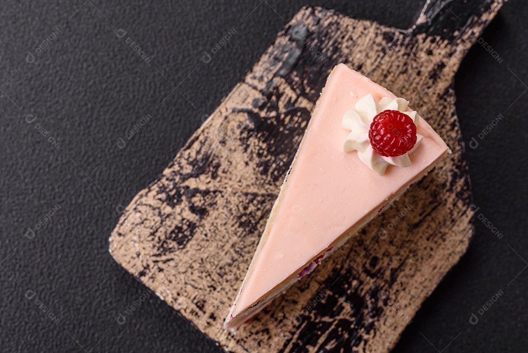 A imagem mostra uma fatia de bolo ou torta com cobertura rosa claro e um topo decorado com uma framboesa fresca