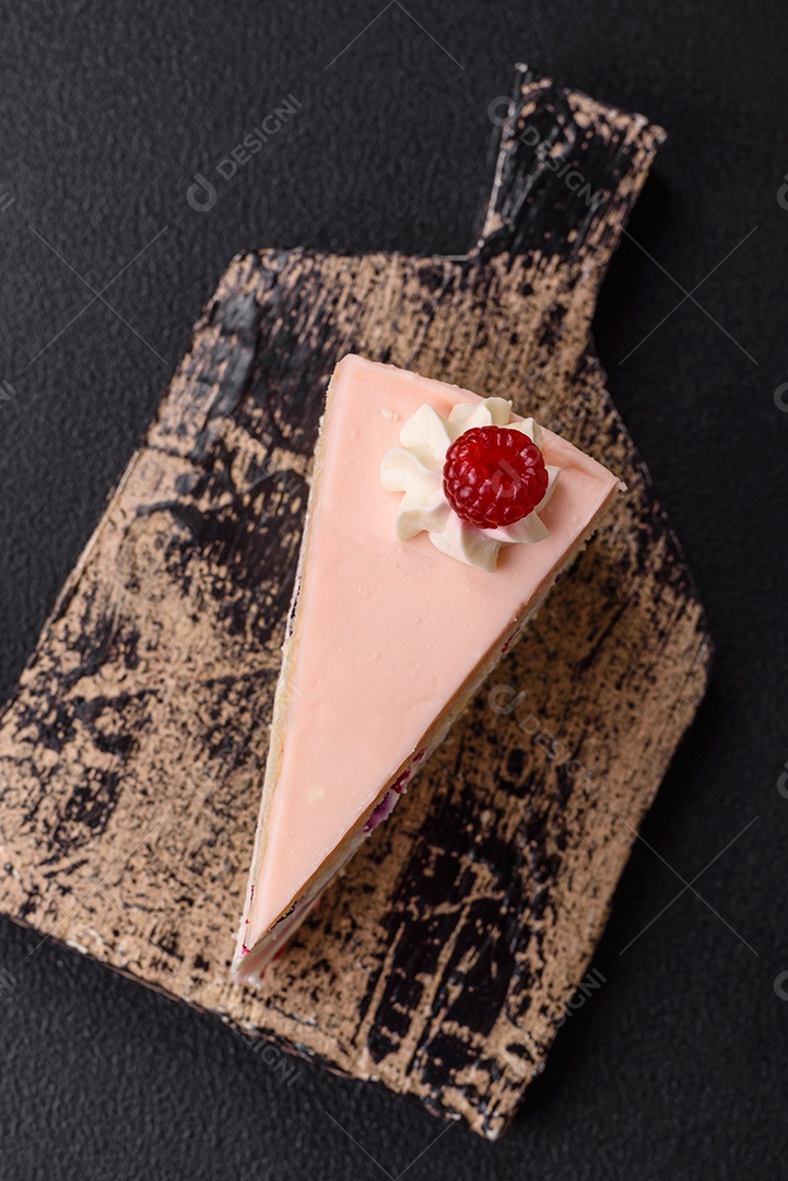 A imagem mostra uma fatia de bolo ou torta com cobertura rosa claro e um topo decorado com uma framboesa fresca