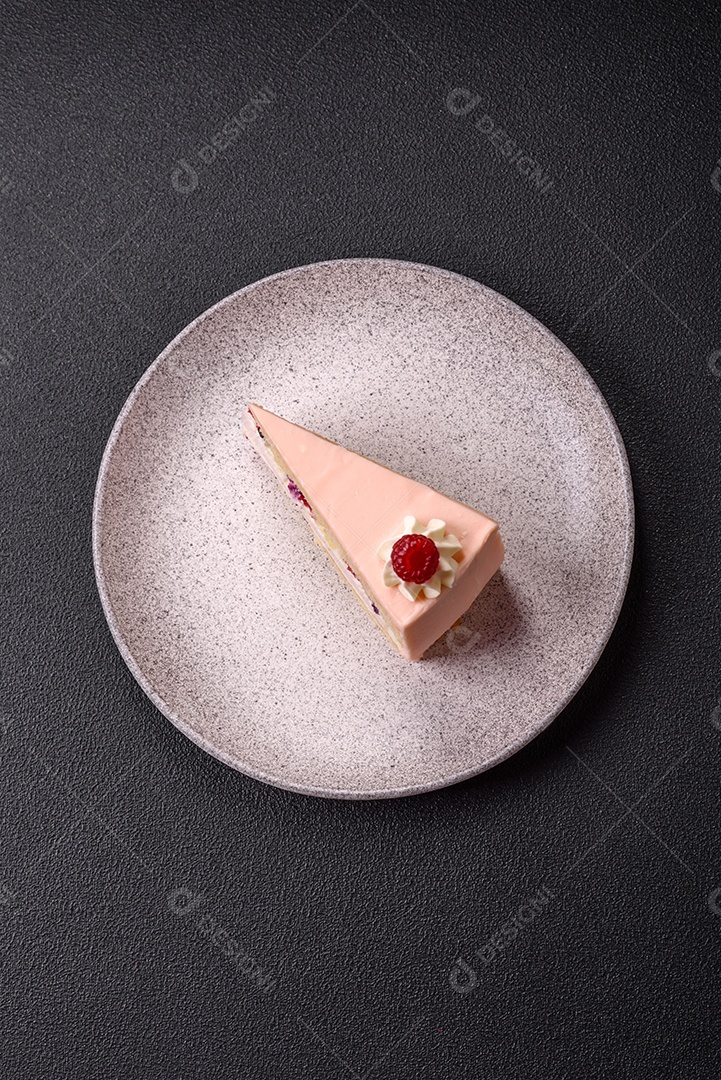 A imagem mostra uma fatia de bolo ou torta com cobertura rosa claro e um topo decorado com uma framboesa fresca