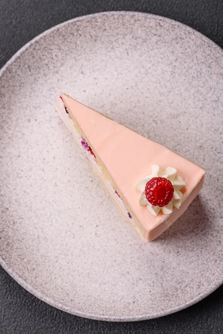 A imagem mostra uma fatia de bolo ou torta com cobertura rosa claro e um topo decorado com uma framboesa fresca