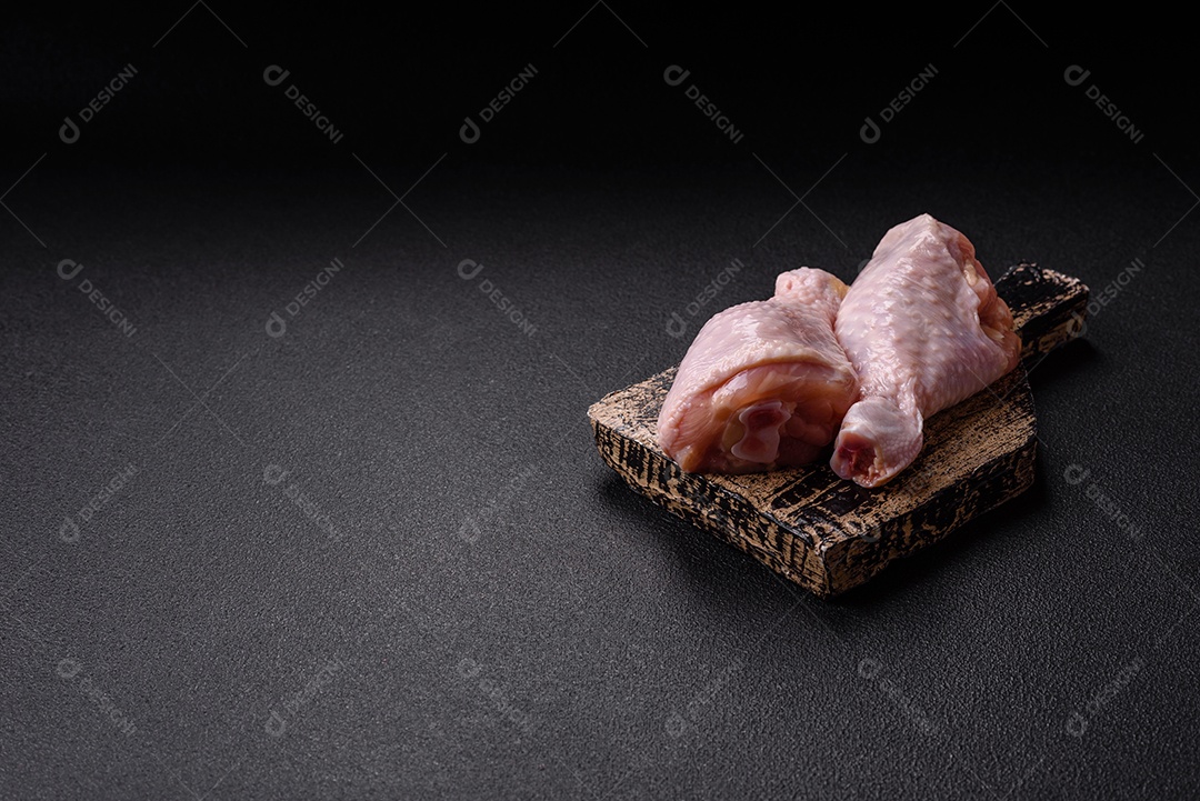 A imagem mostra coxas de frango cruas em um prato, acompanhadas de tomates cereja e ervas frescas.