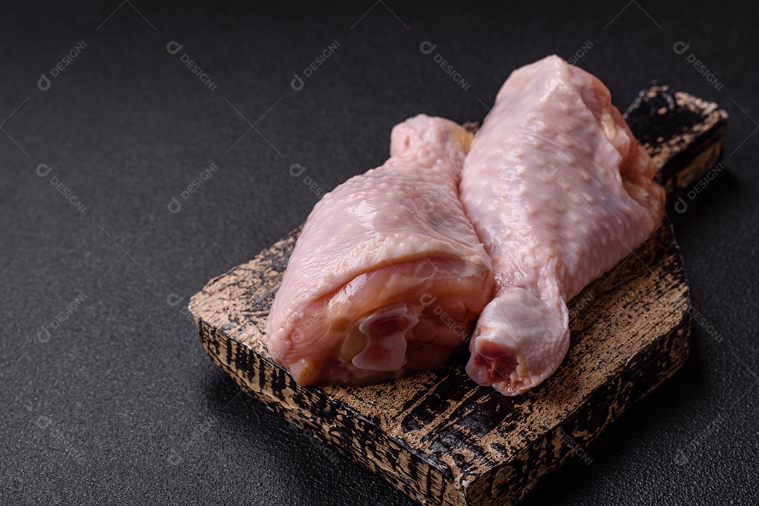 A imagem mostra coxas de frango cruas em um prato, acompanhadas de tomates cereja e ervas frescas.