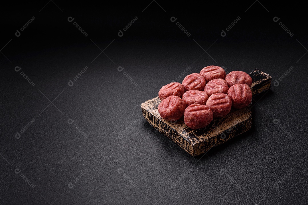 A imagem mostra almôndegas de carne cruas, prontas para serem cozidas, acompanhadas de tomates e pimenta rosa.