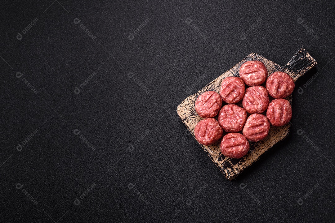 A imagem mostra almôndegas de carne cruas, prontas para serem cozidas, acompanhadas de tomates e pimenta rosa.