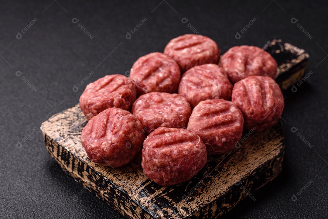 A imagem mostra almôndegas de carne cruas, prontas para serem cozidas, acompanhadas de tomates e pimenta rosa.