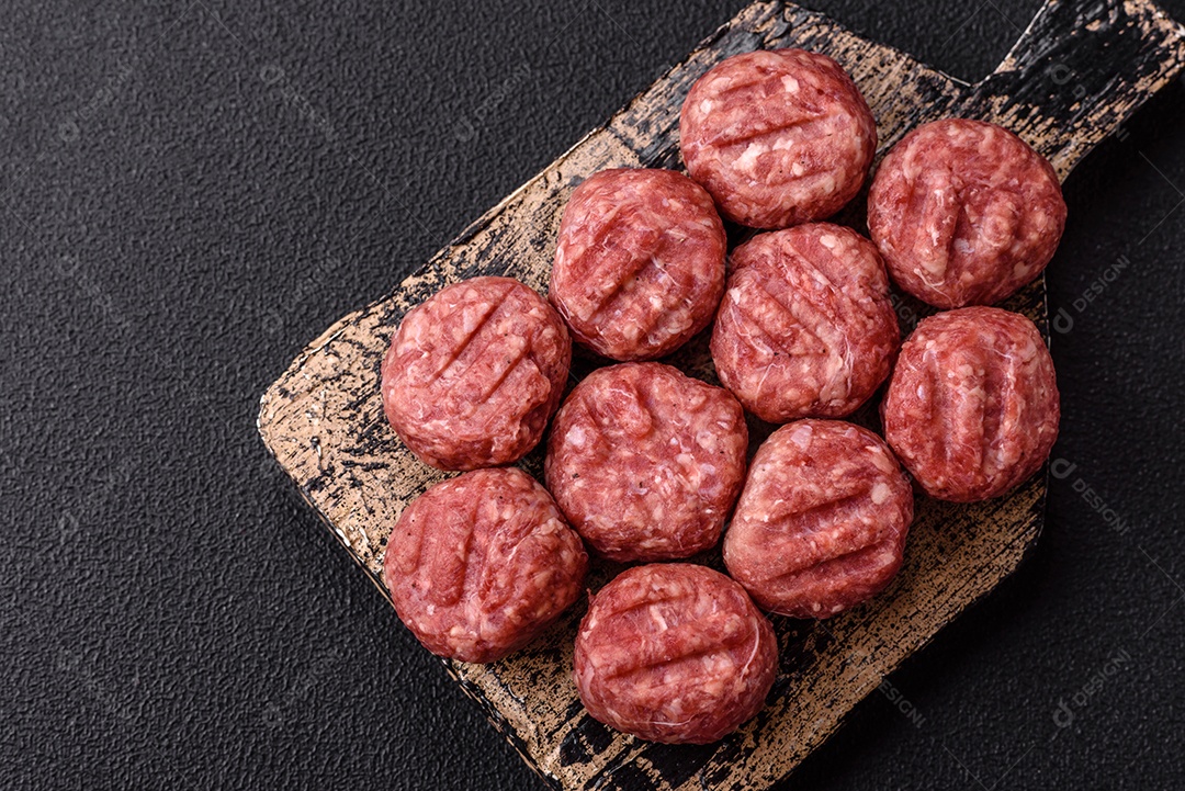 A imagem mostra almôndegas de carne cruas, prontas para serem cozidas, acompanhadas de tomates e pimenta rosa.