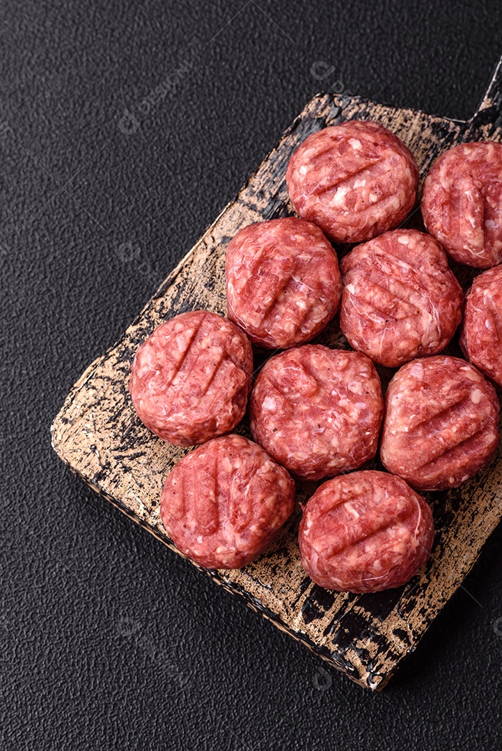A imagem mostra almôndegas de carne cruas, prontas para serem cozidas, acompanhadas de tomates e pimenta rosa.