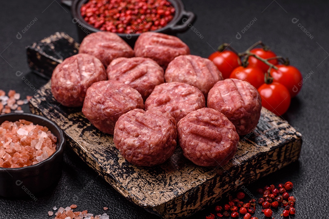 A imagem mostra almôndegas de carne cruas, prontas para serem cozidas, acompanhadas de tomates e pimenta rosa.