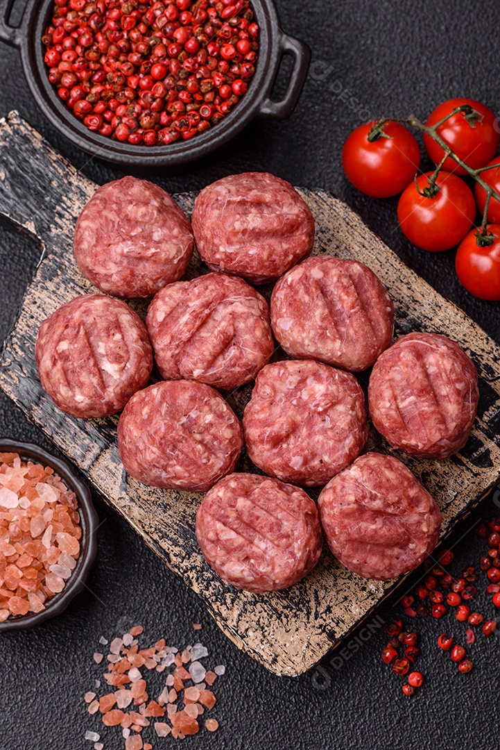 A imagem mostra almôndegas de carne cruas, prontas para serem cozidas, acompanhadas de tomates e pimenta rosa.