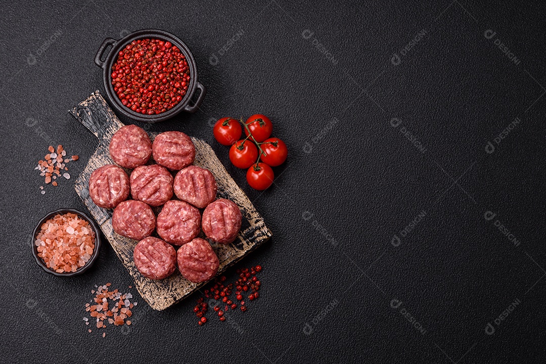 A imagem mostra almôndegas de carne cruas, prontas para serem cozidas, acompanhadas de tomates e pimenta rosa.