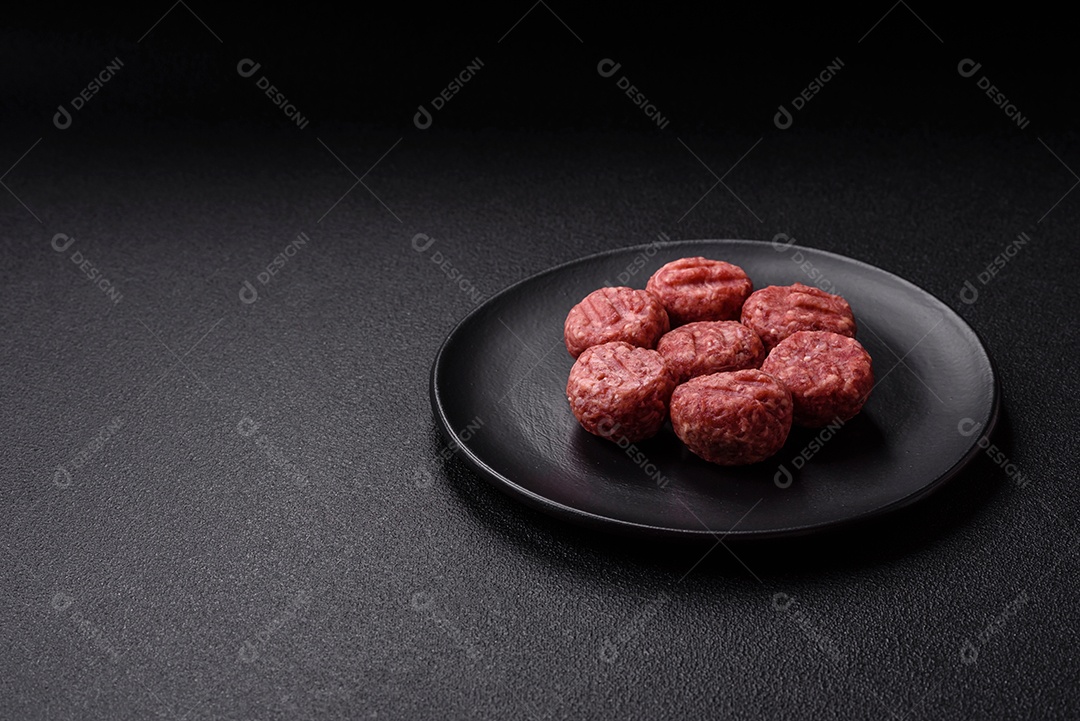 A imagem mostra almôndegas de carne cruas, prontas para serem cozidas, acompanhadas de tomates e pimenta rosa.