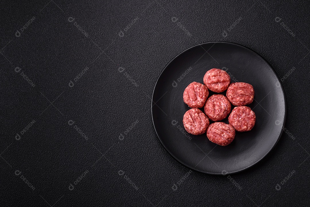 A imagem mostra almôndegas de carne cruas, prontas para serem cozidas, acompanhadas de tomates e pimenta rosa.