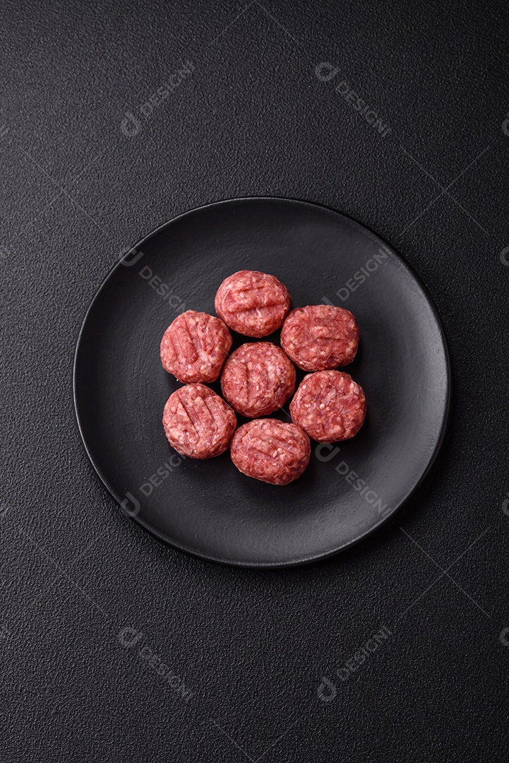 A imagem mostra almôndegas de carne cruas, prontas para serem cozidas, acompanhadas de tomates e pimenta rosa.