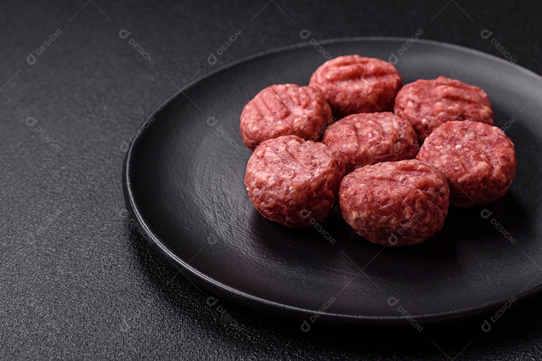 A imagem mostra almôndegas de carne cruas, prontas para serem cozidas, acompanhadas de tomates e pimenta rosa.