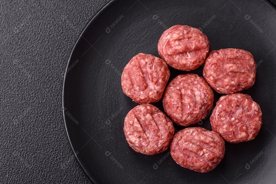 A imagem mostra almôndegas de carne cruas, prontas para serem cozidas, acompanhadas de tomates e pimenta rosa.