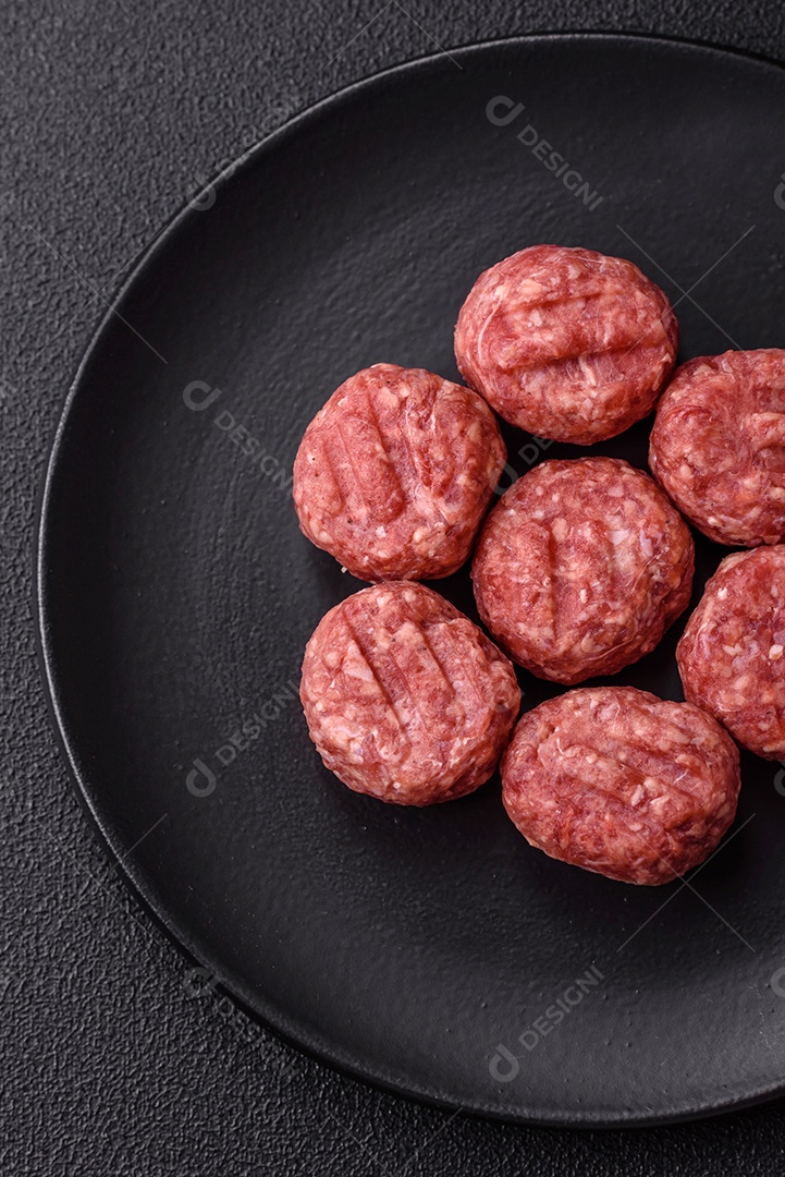 A imagem mostra almôndegas de carne cruas, prontas para serem cozidas, acompanhadas de tomates e pimenta rosa.