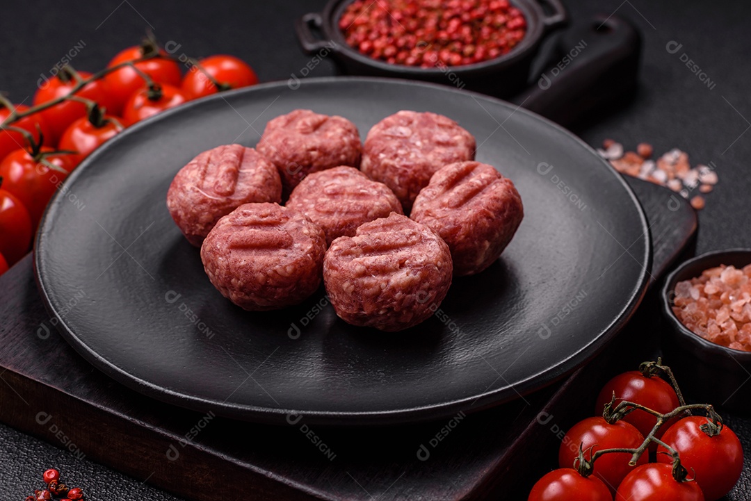 A imagem mostra almôndegas de carne cruas, prontas para serem cozidas, acompanhadas de tomates e pimenta rosa.