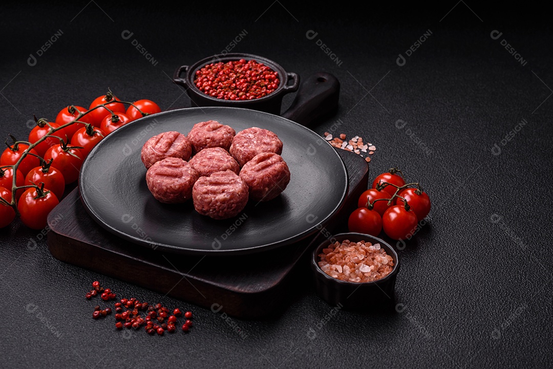 A imagem mostra almôndegas de carne cruas, prontas para serem cozidas, acompanhadas de tomates e pimenta rosa.