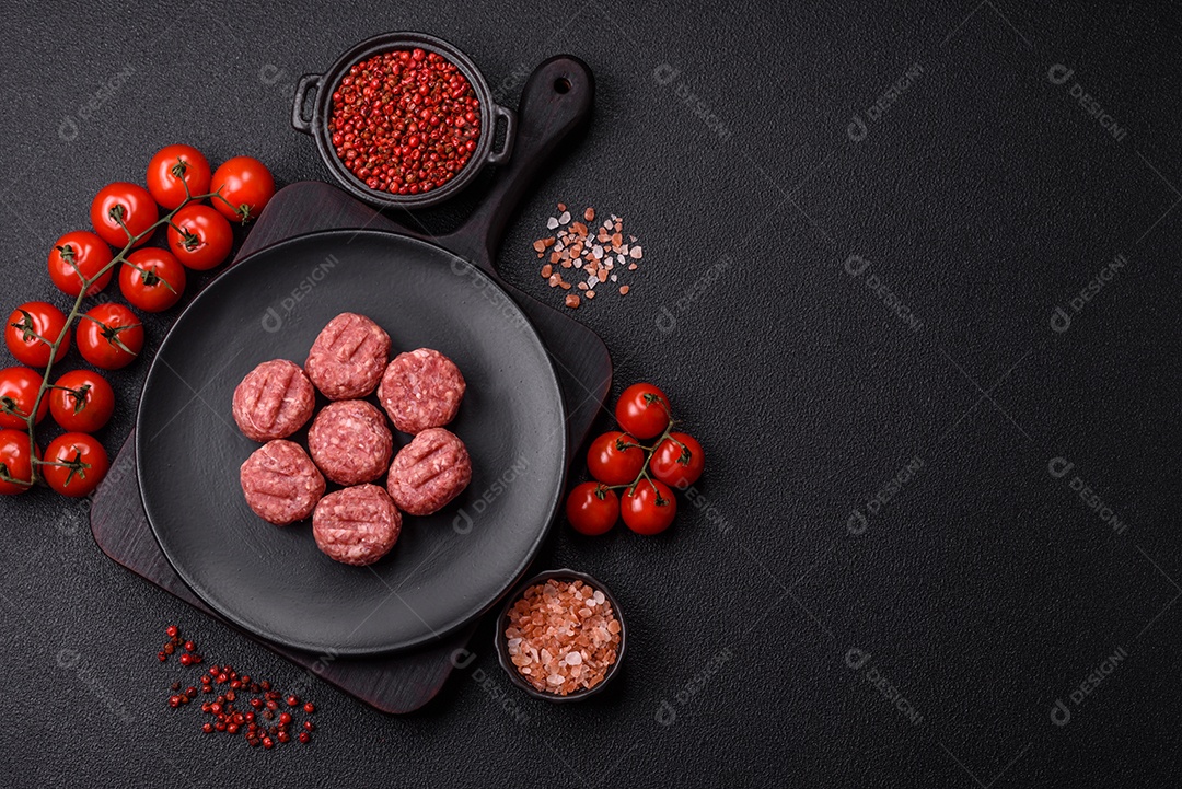 A imagem mostra almôndegas de carne cruas, prontas para serem cozidas, acompanhadas de tomates e pimenta rosa.