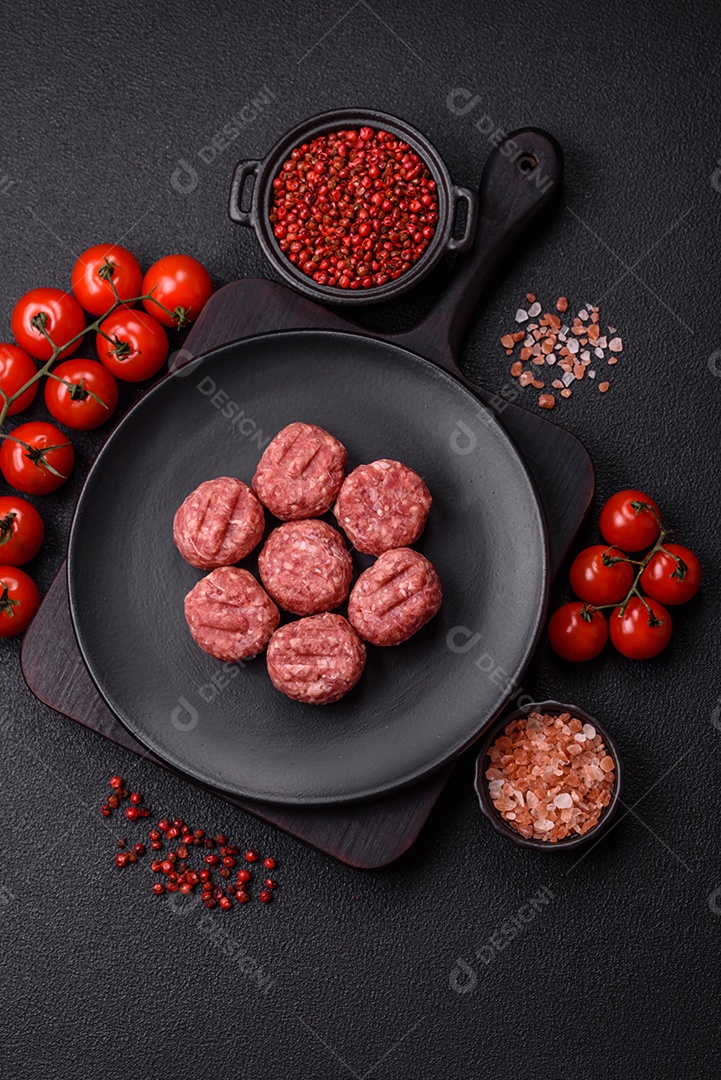 A imagem mostra almôndegas de carne cruas, prontas para serem cozidas, acompanhadas de tomates e pimenta rosa.