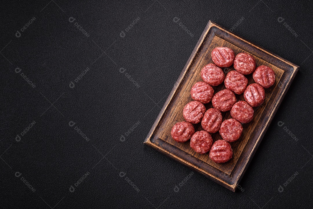 A imagem mostra almôndegas de carne cruas, prontas para serem cozidas, acompanhadas de tomates e pimenta rosa.
