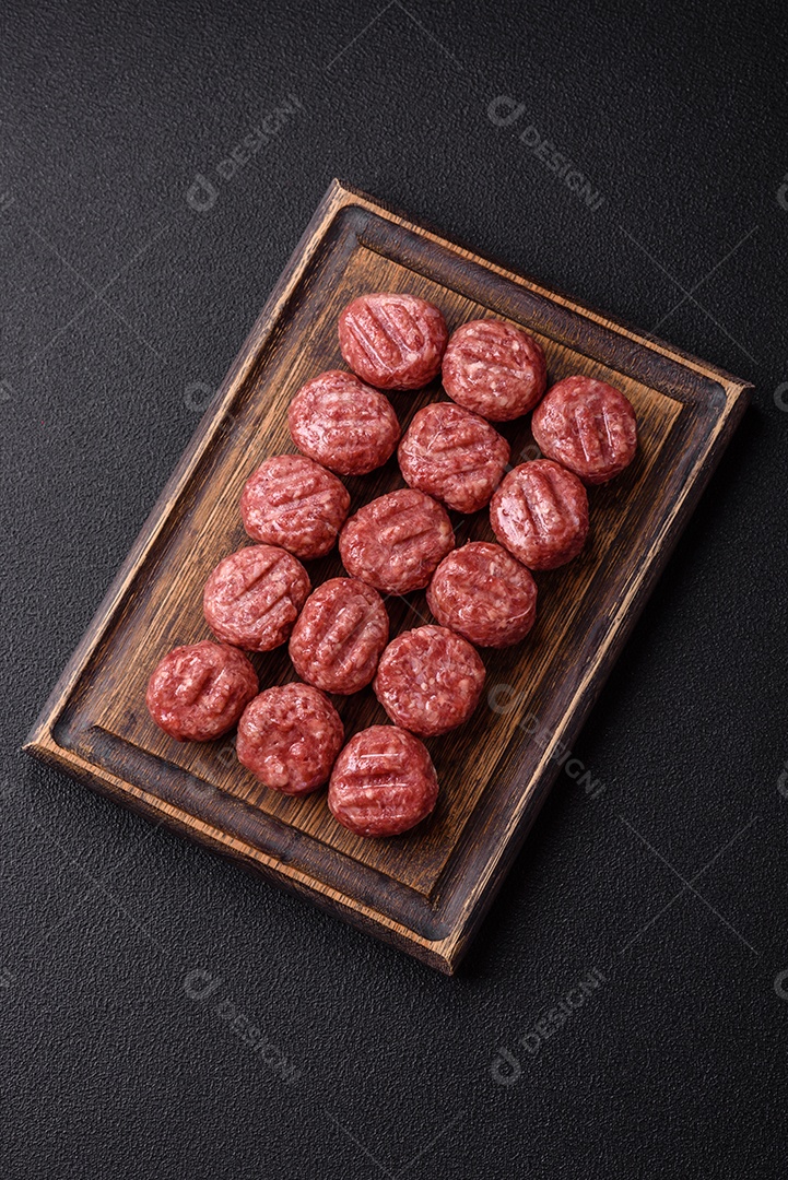 A imagem mostra almôndegas de carne cruas, prontas para serem cozidas, acompanhadas de tomates e pimenta rosa.