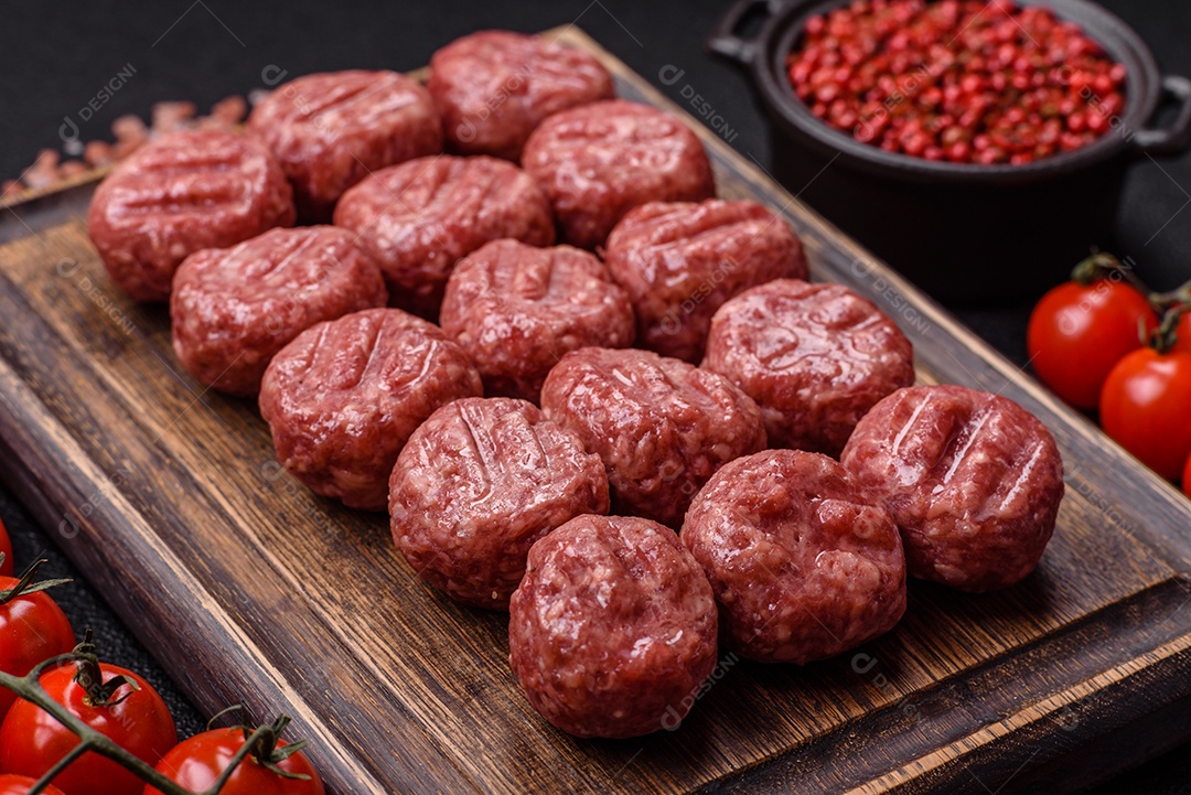 A imagem mostra almôndegas de carne cruas, prontas para serem cozidas, acompanhadas de tomates e pimenta rosa.