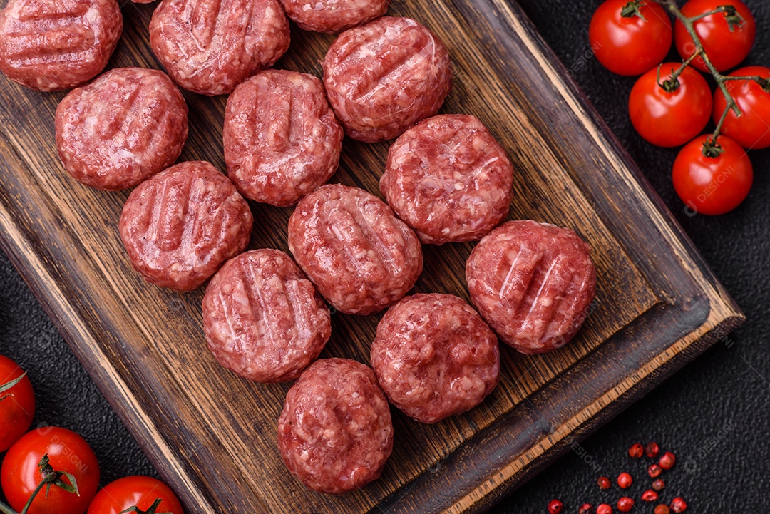 A imagem mostra almôndegas de carne cruas, prontas para serem cozidas, acompanhadas de tomates e pimenta rosa.