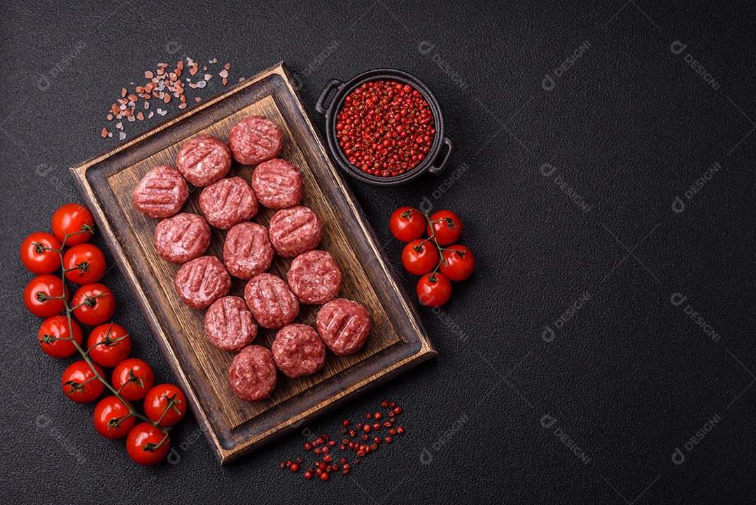 A imagem mostra almôndegas de carne cruas, prontas para serem cozidas, acompanhadas de tomates e pimenta rosa.