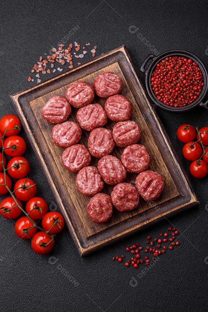 A imagem mostra almôndegas de carne cruas, prontas para serem cozidas, acompanhadas de tomates e pimenta rosa.