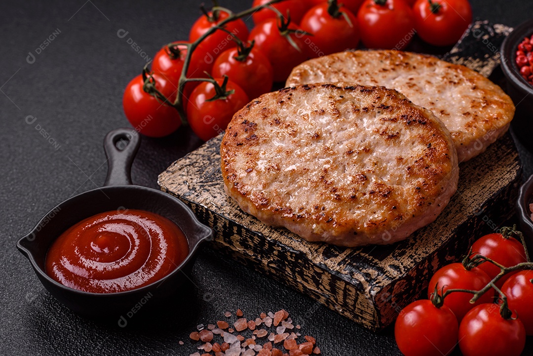 A imagem mostra chuletas de porco grelhadas, acompanhadas de ramos de tomilho e tomates cereja.