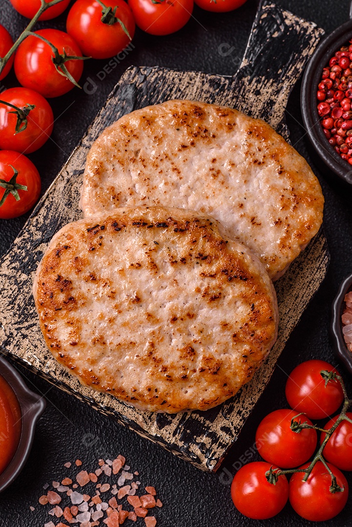 A imagem mostra chuletas de porco grelhadas, acompanhadas de ramos de tomilho e tomates cereja.