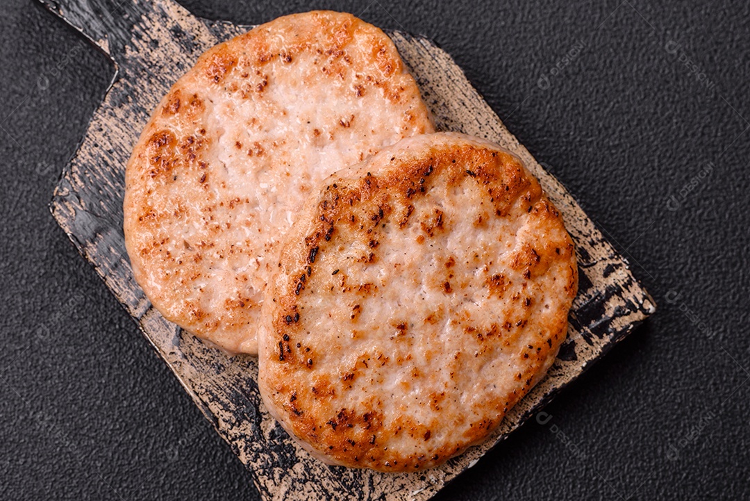 A imagem mostra chuletas de porco grelhadas, acompanhadas de ramos de tomilho e tomates cereja.