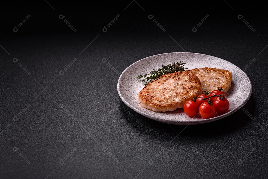 A imagem mostra chuletas de porco grelhadas, acompanhadas de ramos de tomilho e tomates cereja.