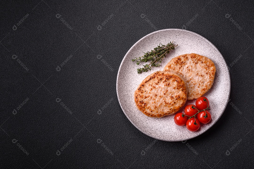 A imagem mostra chuletas de porco grelhadas, acompanhadas de ramos de tomilho e tomates cereja.